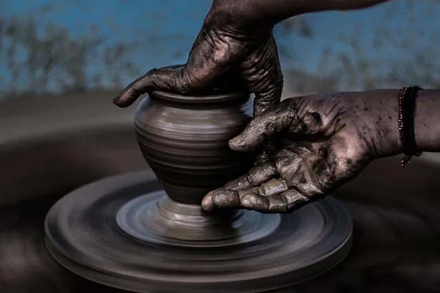 Hands shaping clay on a potter's wheel