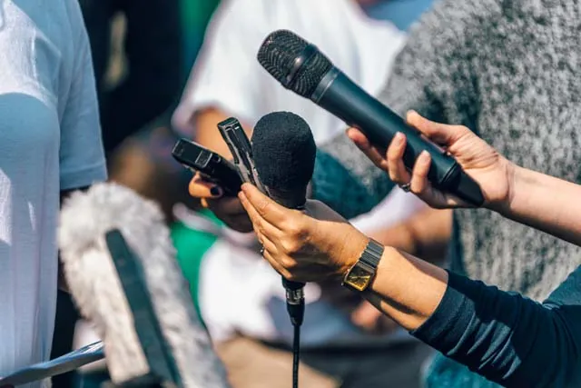 Journalists holding microphones at a press briefing